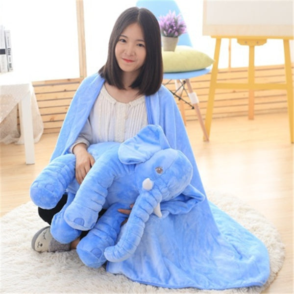 Woman sitting on floor holding blue elephant plush baby comfort sleep pillow wrapped in matching blue blanket