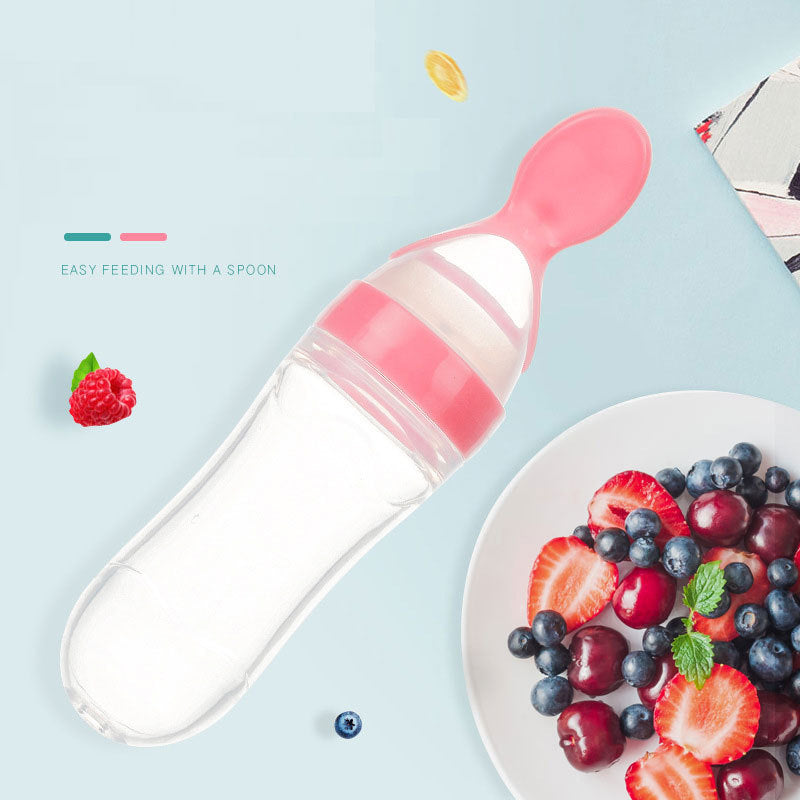 Pink baby food supplement feeder with a spoon for easy feeding next to a plate of fresh berries
