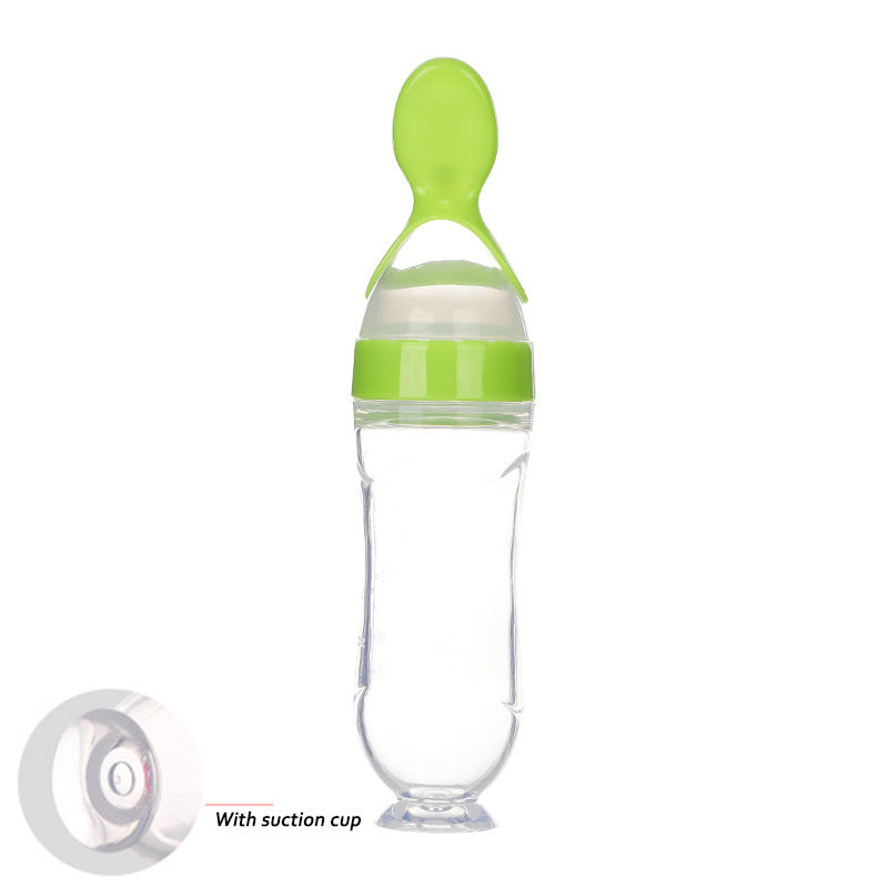 Clear baby food supplement feeder with green lid and attached spoon featuring a suction cup base