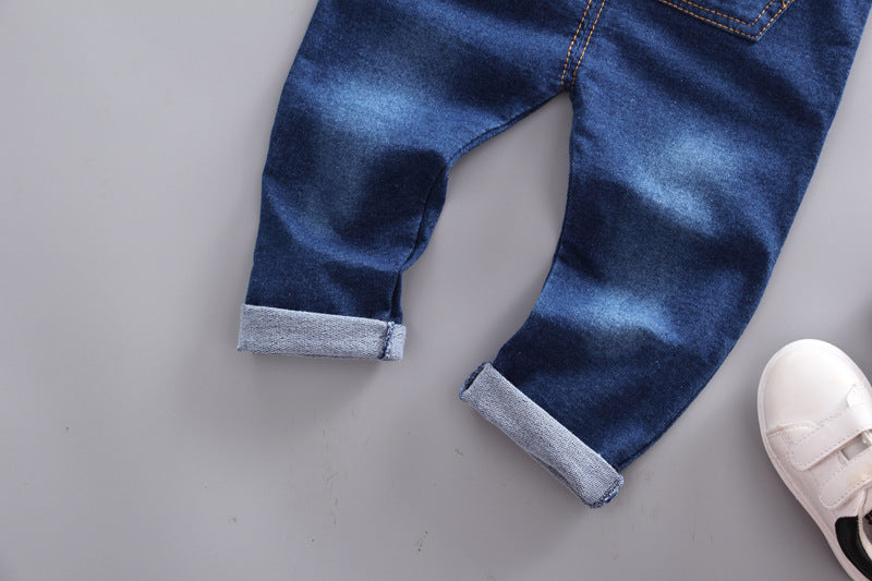 Close-up of rolled cuffs on blue denim overalls for baby boys displayed on gray background