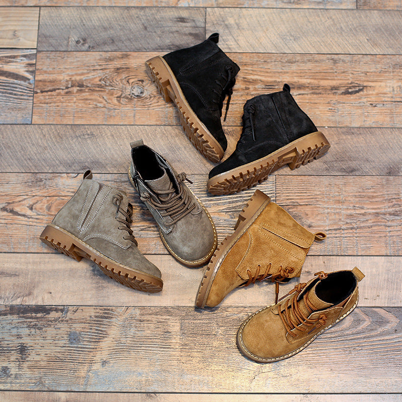 Boys black Martin boots with tan and gray suede ankle boots on wooden floor