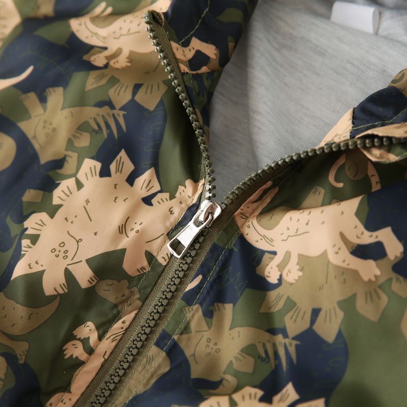 Close-up of boys hooded jacket with dinosaur print and zipper on green and navy fabric