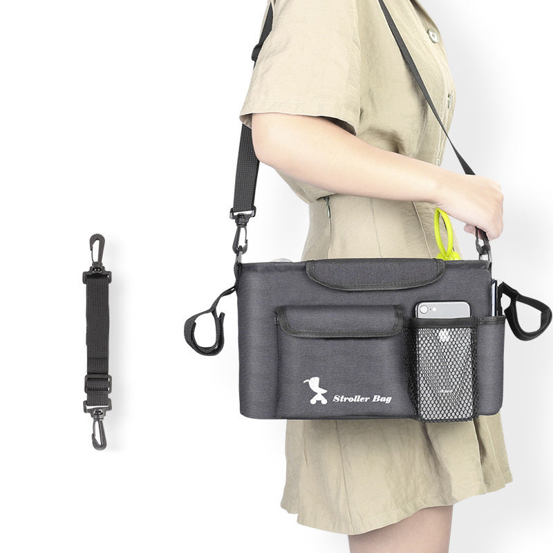 Black baby essentials organizer for stroller with multiple pockets carried by a person in beige dress