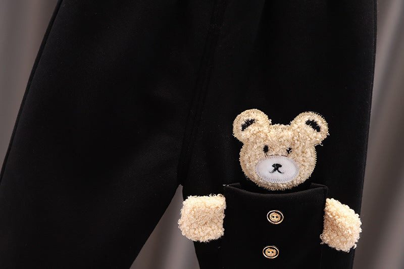 Close-up of warm toddler clothes set featuring black fabric and a teddy bear applique on the sleeve