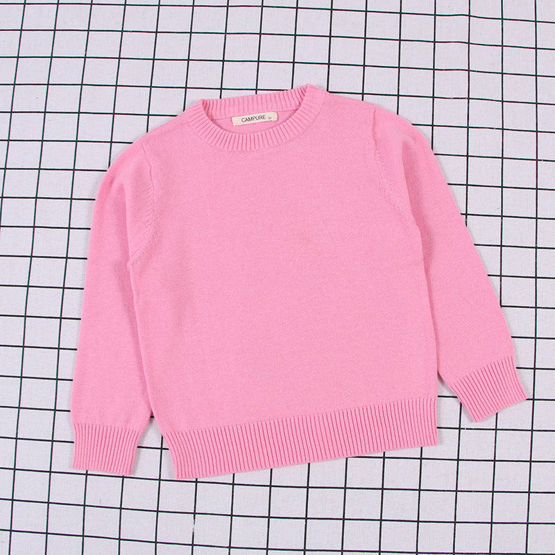 Pink solid color toddler sweater with ribbed cuffs and hem on checkered background