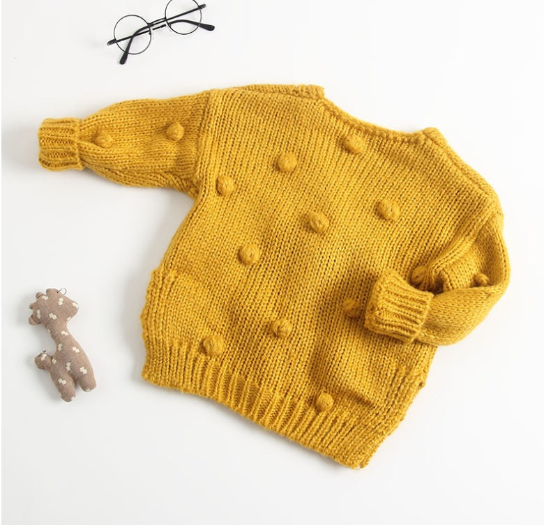 Mustard yellow knitted cute toddler cardigan for girls with pompom details on white background
