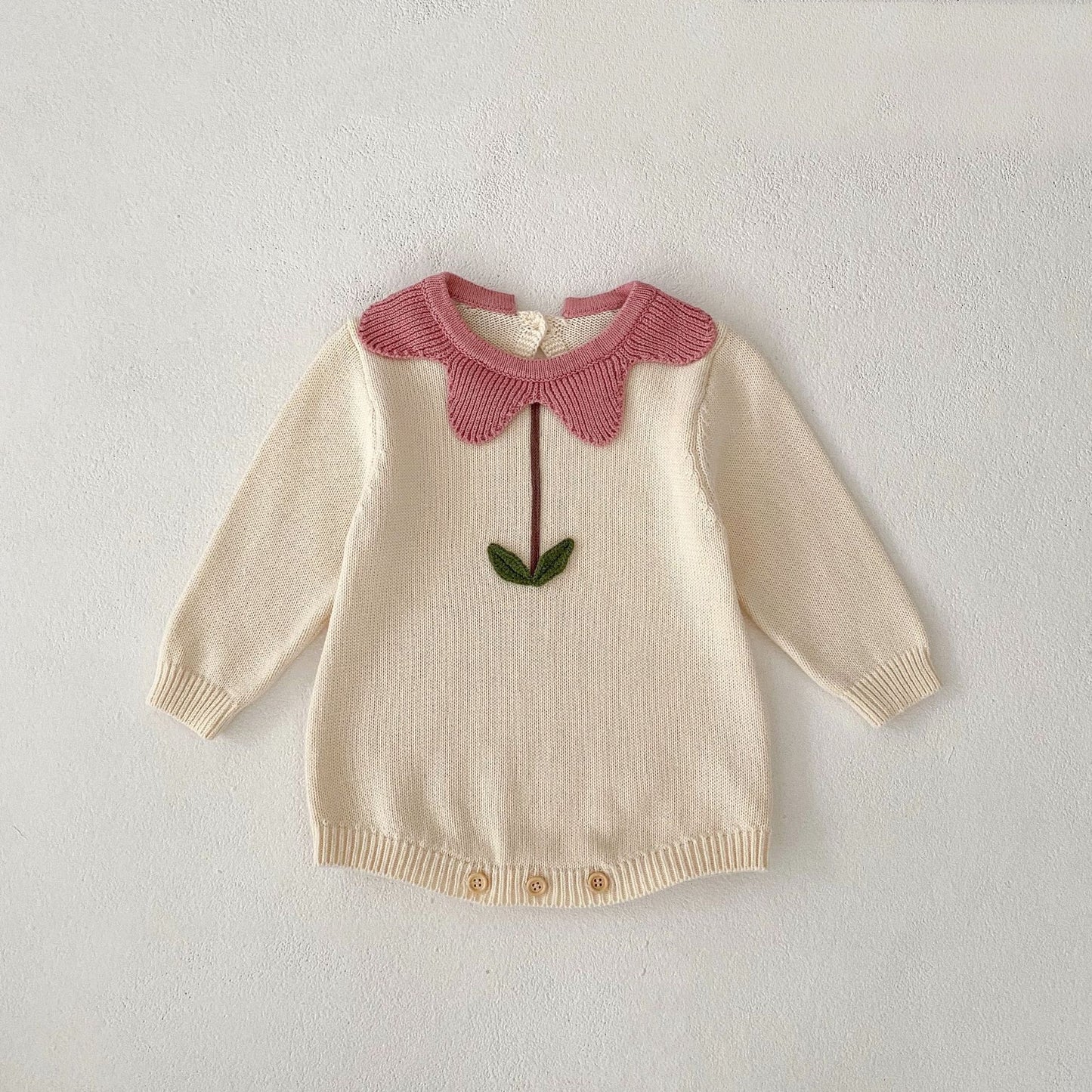 Cream and pink floral newborn sweater with long sleeves and button closure at bottom
