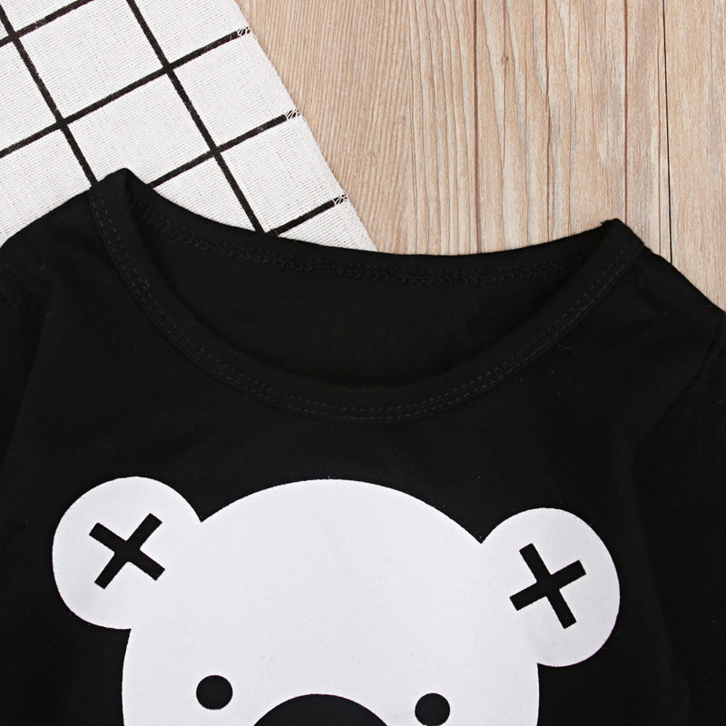 Black top with cute bear face print part of a two piece kids loungewear set on wooden background