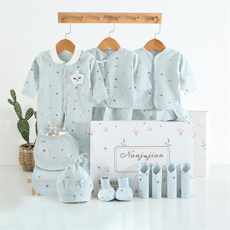 Newborn baby clothes gift set in light blue with star patterns including bodysuits, hats, booties, and bibs displayed with gift box