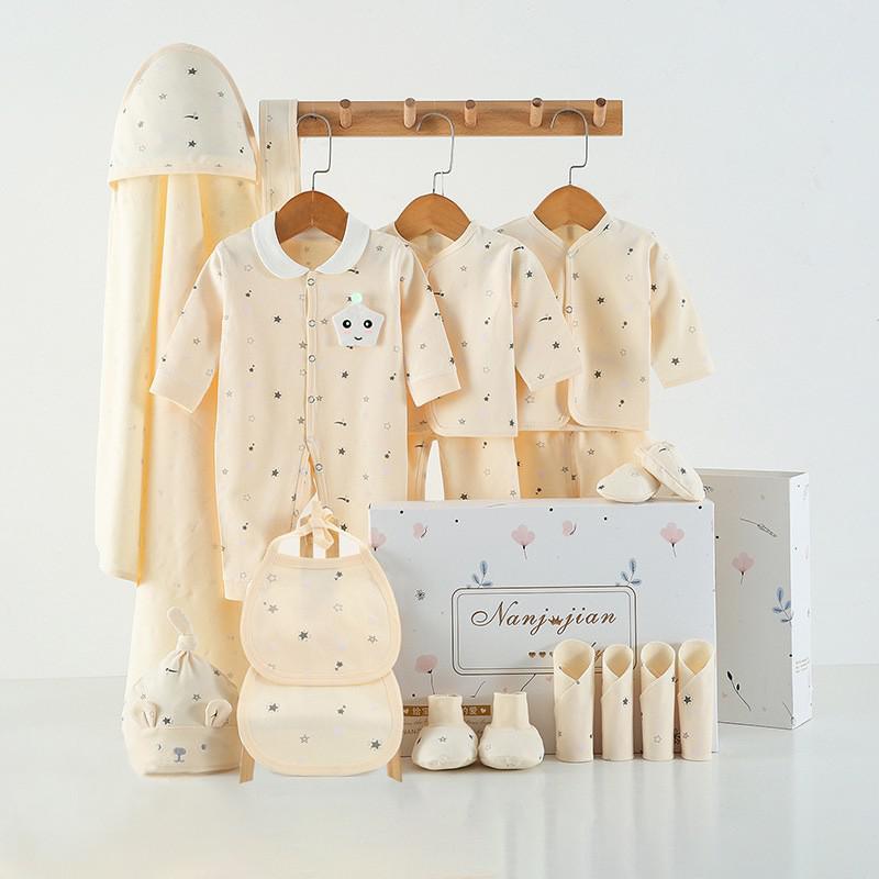 Newborn baby clothes gift set with soft cream outfit, bibs, hat, booties, and hooded towel in a decorative box