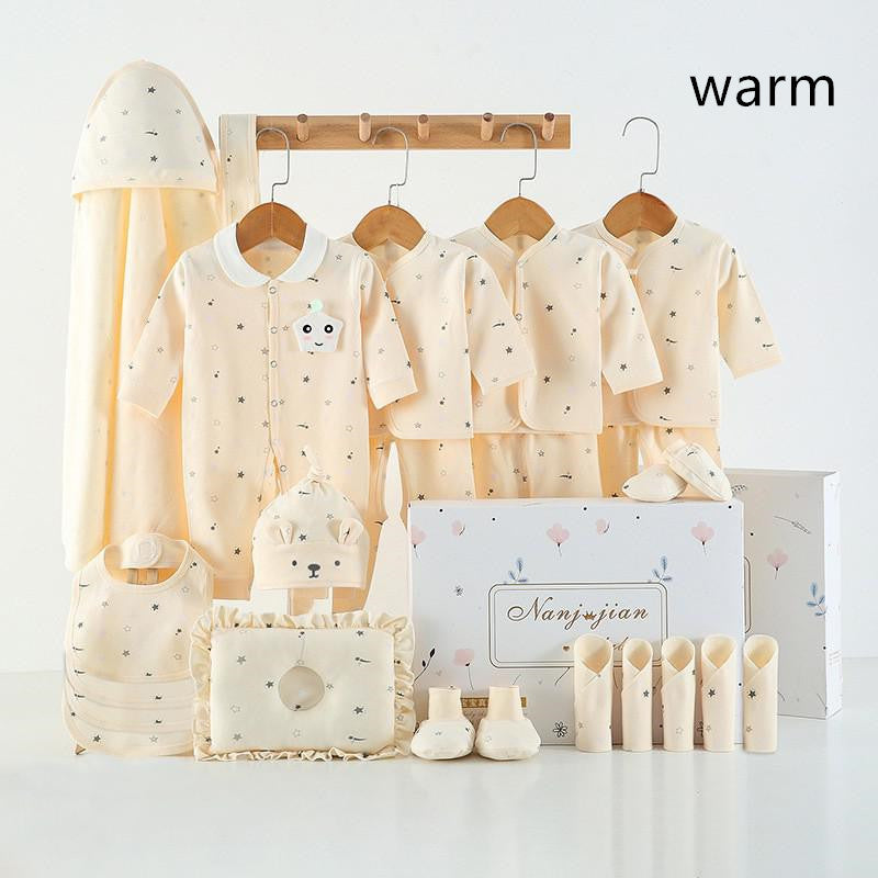 Newborn baby clothes gift set in soft cream color with stars and animal designs including bodysuits, hats, booties, and a hooded towel