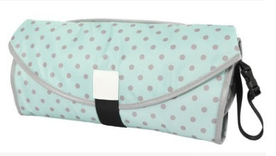 Portable baby changing pad with gray polka dots on light blue and black strap for easy carrying