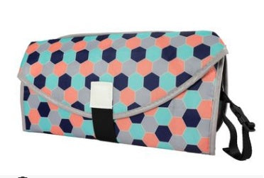Portable baby changing pad with colorful hexagon pattern and secure black strap for easy carrying