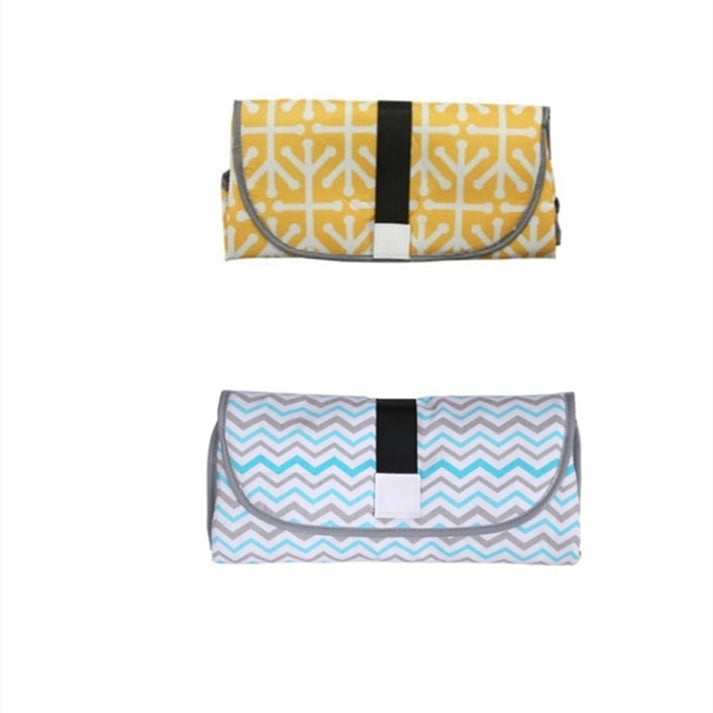 Two folded portable baby changing pads in yellow and gray patterns with black straps