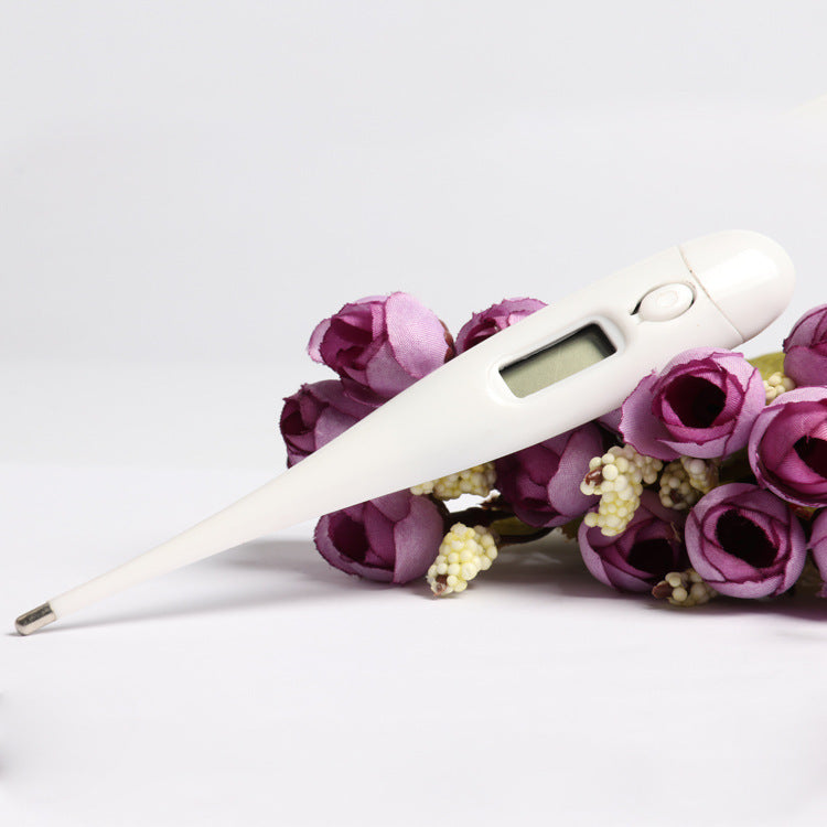 White digital reliable fever thermometer for babies placed on purple flowers with a clear display and on button
