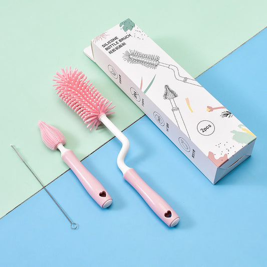 Pink baby bottle cleaning brush set with silicone bristles and cleaning tool on pastel background