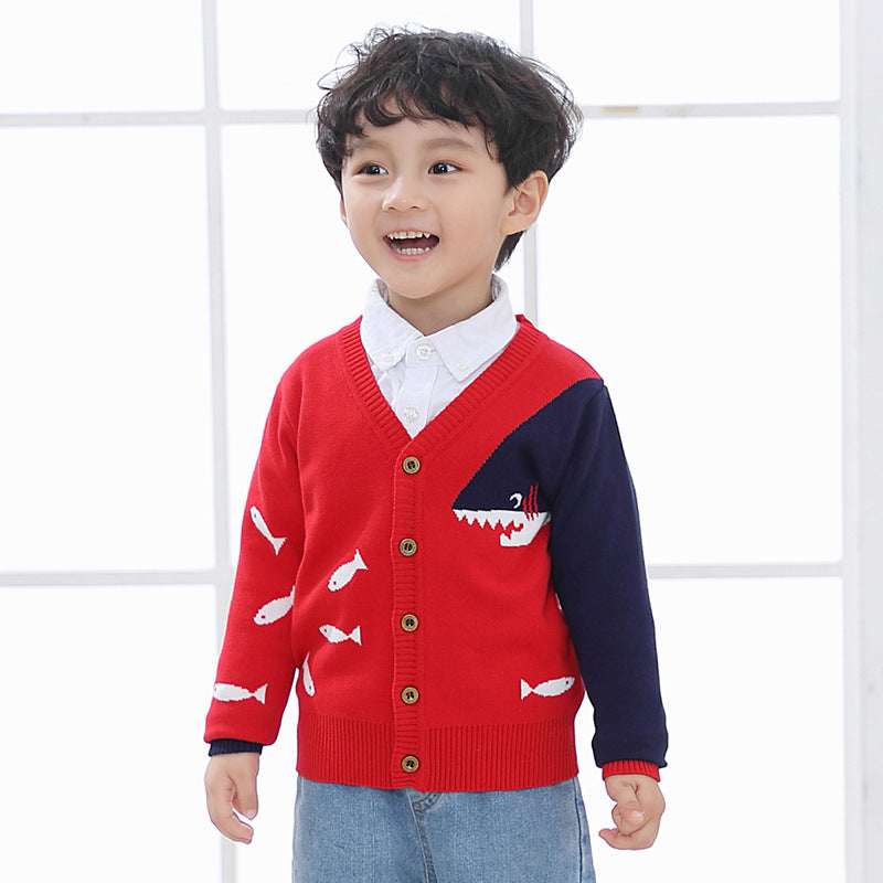 Smiling child wearing a red and navy children's V-neck cardigan with fish and shark design