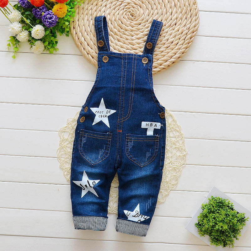 Dark blue denim bib jeans for toddlers with star patches and button straps on white background