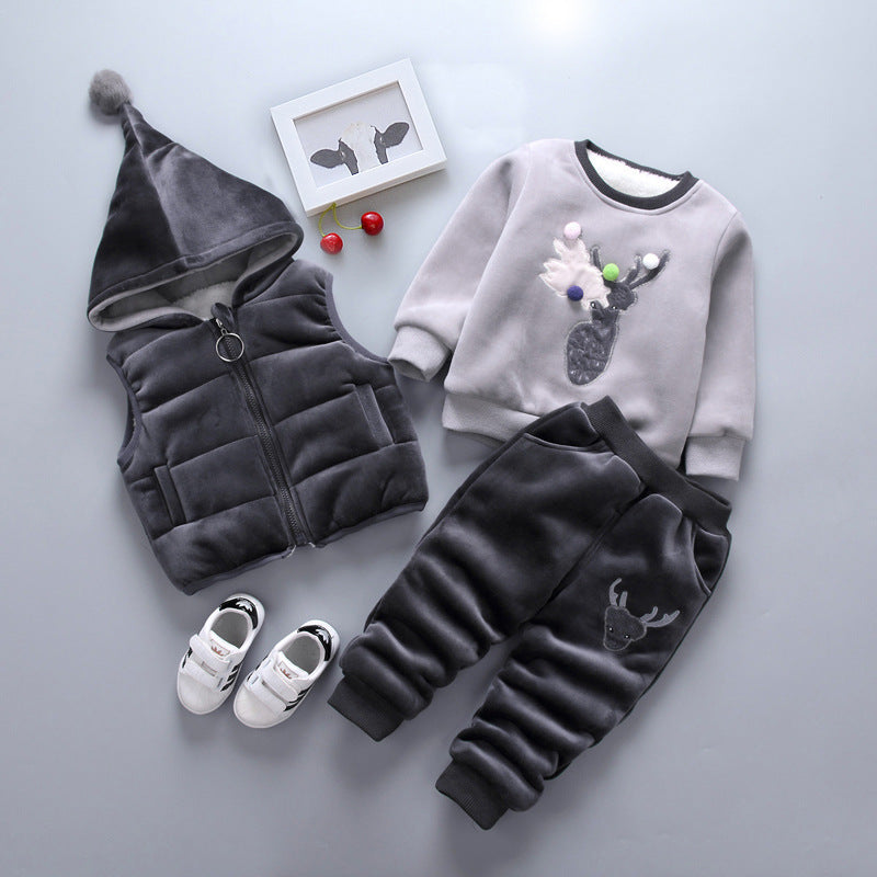 Warm toddler clothes for winter including gray hooded vest, reindeer sweater, black pants, and white shoes