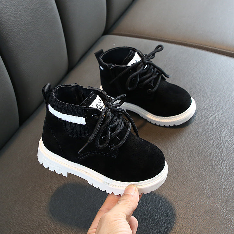Black baby boots with soft soles featuring white accents and lace-up design on a gray surface