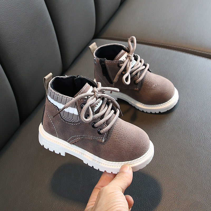 Brown baby boots with soft soles and white lace-up design placed on a gray surface