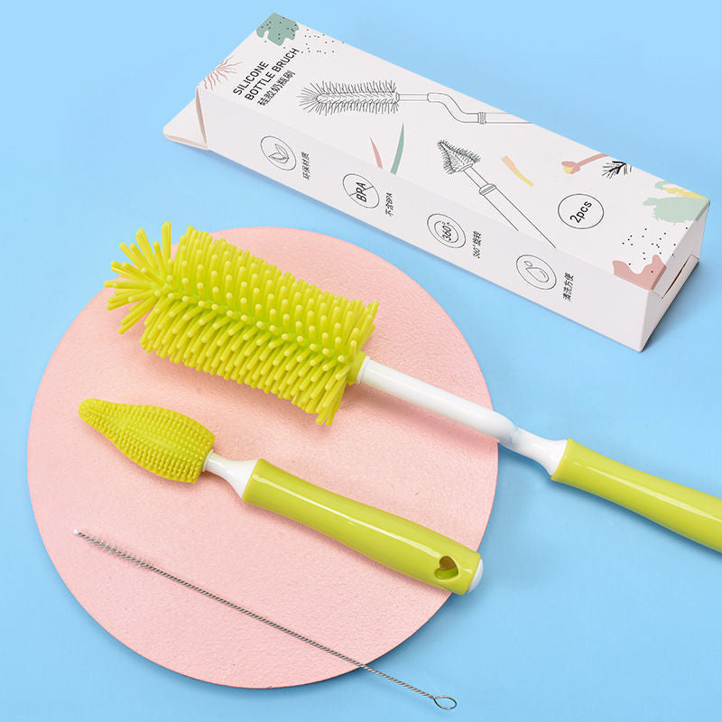 Green baby bottle cleaning brush set with silicone bristles and wire detail brush on blue and pink background