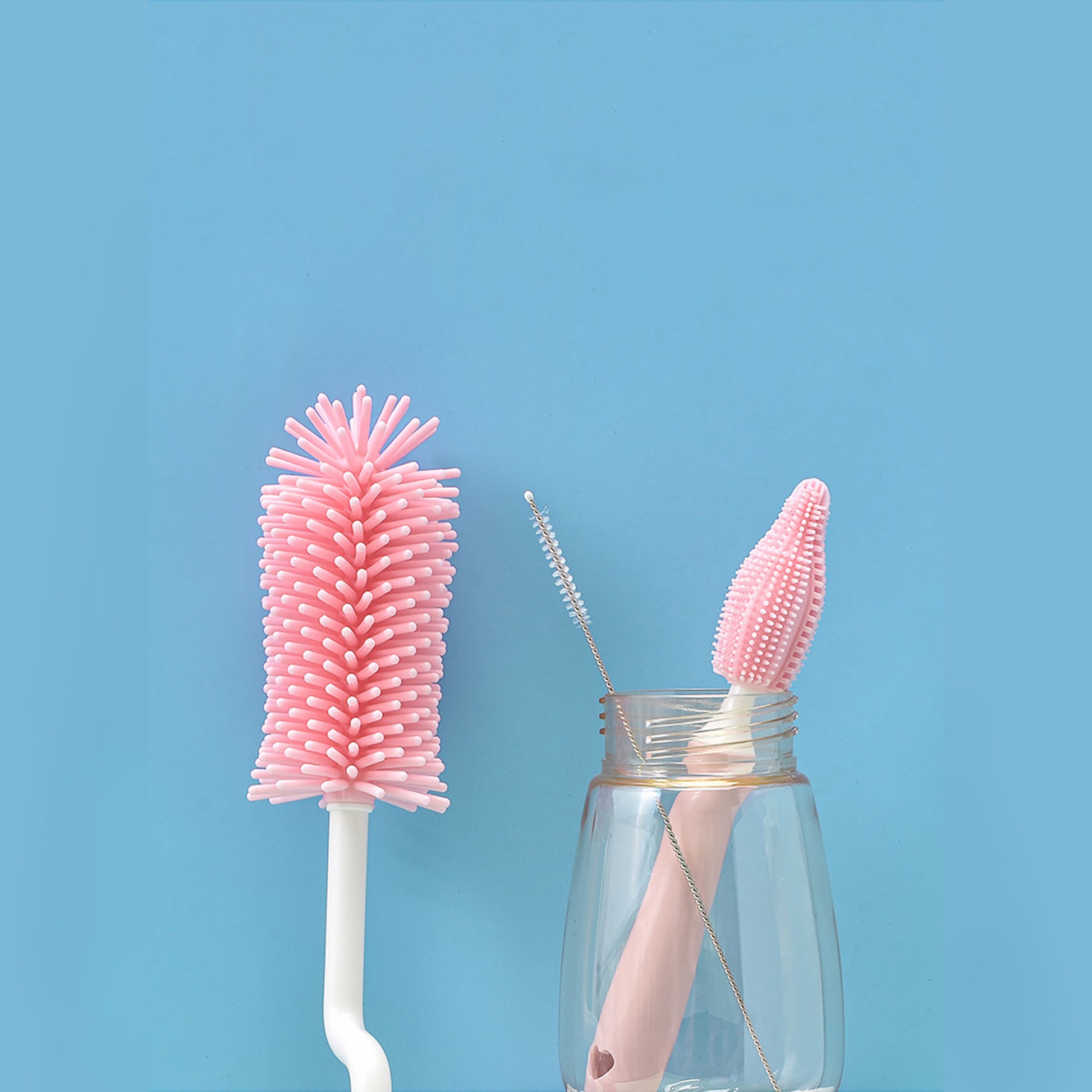 Pink baby bottle cleaning brush set with different brush sizes against a blue background