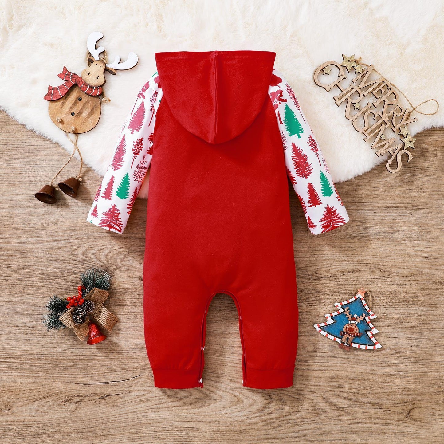 Red baby Christmas onesie with tree patterned white sleeves and hood laid flat on wooden surface