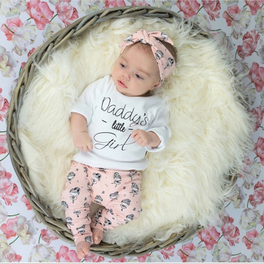 Baby wearing a pink baby girl clothes set with printed pants, matching headband, and white sweatshirt saying Daddys little girl
