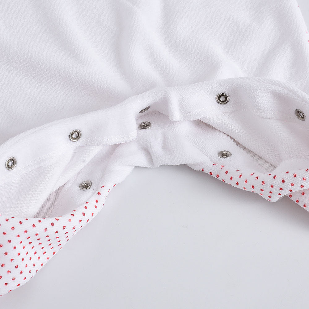 Close-up of white Christmas baby onesie with red polka dot trim and snap buttons for easy dressing