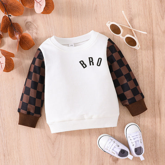 Cute baby plaid sweatshirt with white body and brown checkered sleeves laid flat with white shoes and sunglasses