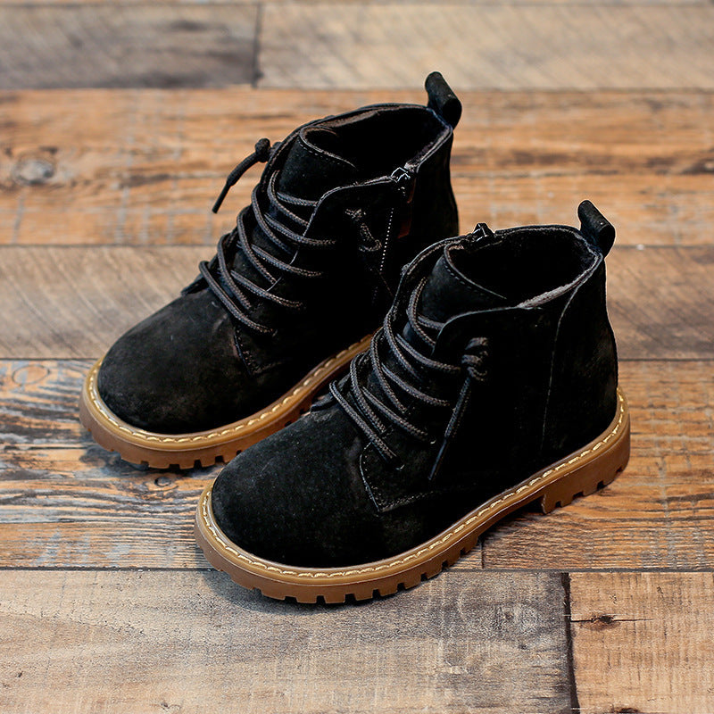 Boys black Martin boots with lace-up design and durable brown sole on wooden floor