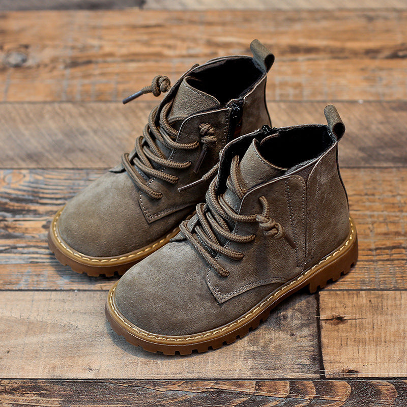 Stylish boys black Martin boots with durable laces and rugged brown sole on wooden floor