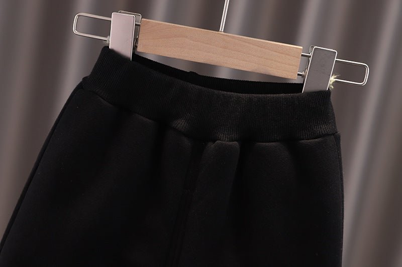 Close-up of black warm toddler clothes set pants hanging on wooden hanger with elastic waistband