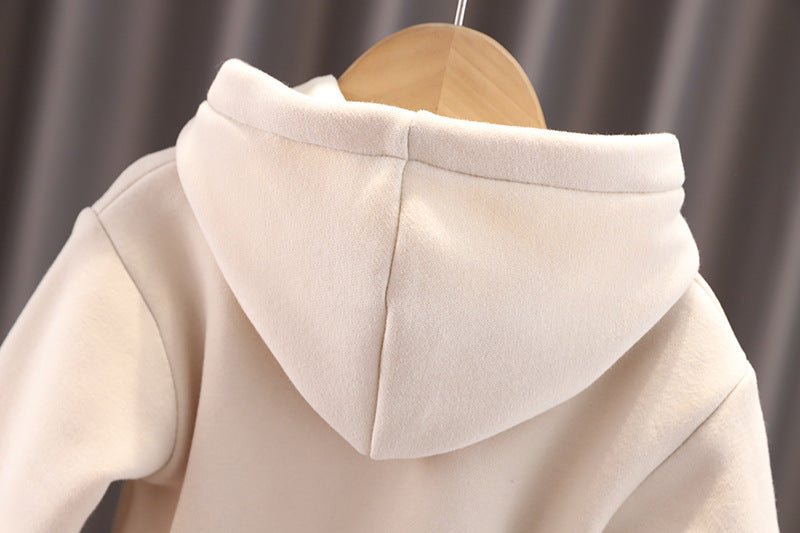 Close-up of soft beige warm toddler clothes set with hood on wooden hanger against gray background