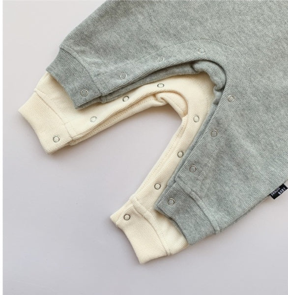 Close-up of grey and cream trendy baby onesies for boys with snap button closures at the legs