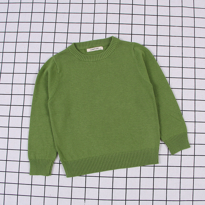 Green solid color toddler sweater with ribbed cuffs and hem laid flat on a grid background