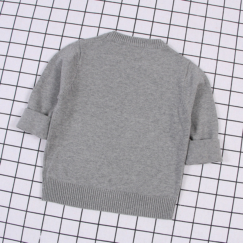 Gray solid color toddler sweater with folded sleeves and ribbed hem on checkered background
