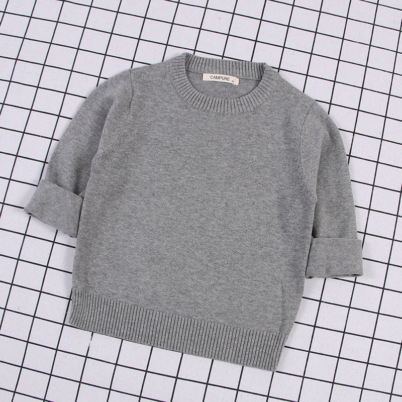 Gray solid color toddler sweater with ribbed cuffs and hem laid flat on grid background