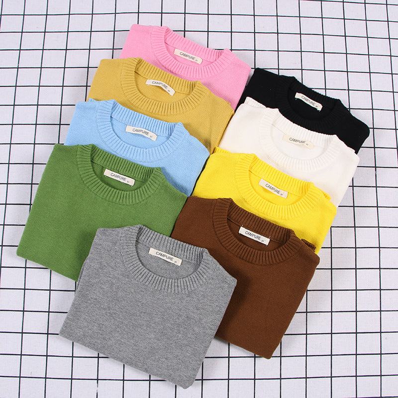Collection of folded solid color toddler sweater in various colors including pink, yellow, green, and black