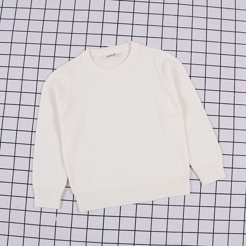 White solid color toddler sweater with long sleeves and ribbed cuffs on grid background