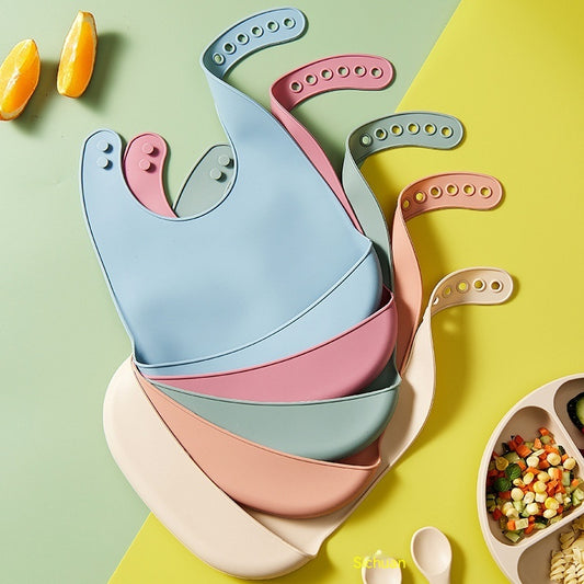 Set of easy clean baby eating bibs in pastel colors with adjustable neck straps on green and yellow background