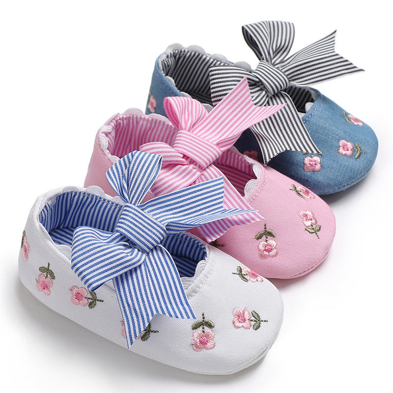 Floral crib shoes for girls in white, pink, and blue with embroidered flowers and striped bows