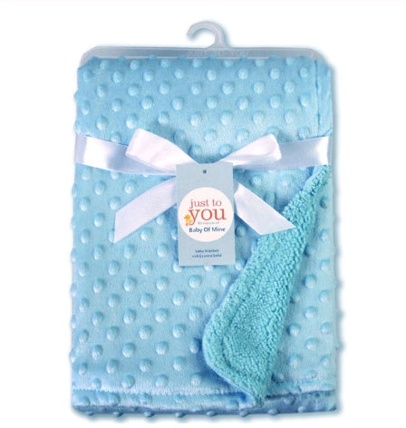 Soft newborn swaddle wrap in light blue with textured dot pattern and white ribbon bow