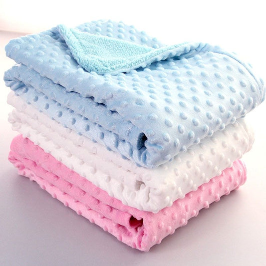Stack of soft newborn swaddle wrap blankets in blue white and pink with textured dots