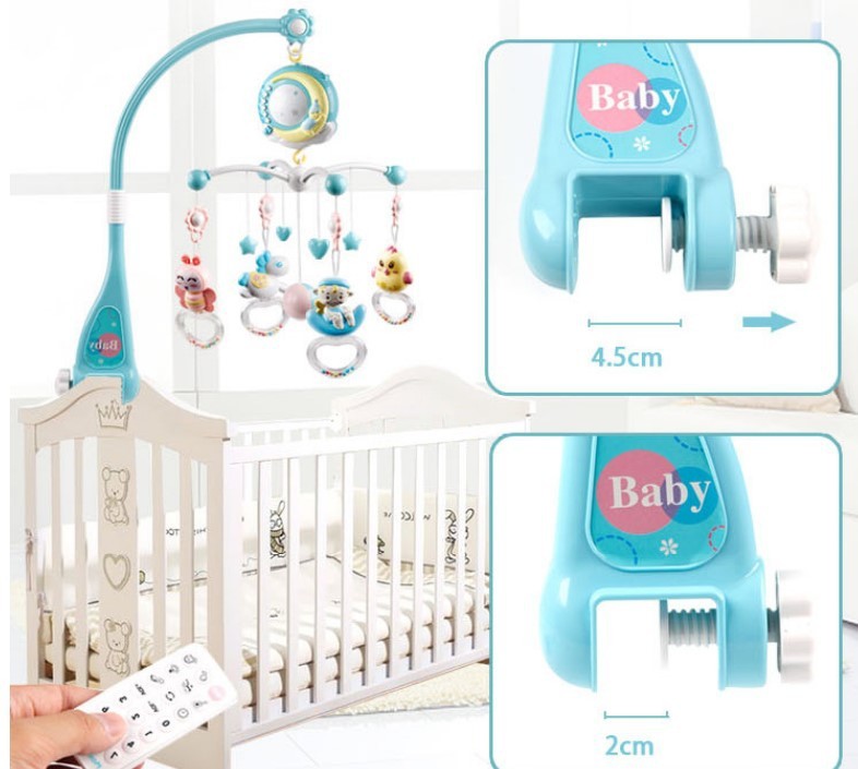 Blue infant soothing mobile with remote control attached to white baby crib with hanging plush toys