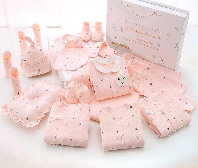 Newborn baby clothes gift set in soft pink with hat, mittens, booties, bib, and clothing items in a gift box