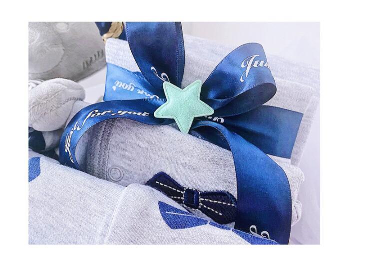 Newborn baby boy gift set wrapped with blue ribbon and star-shaped decoration in a soft grey fabric box