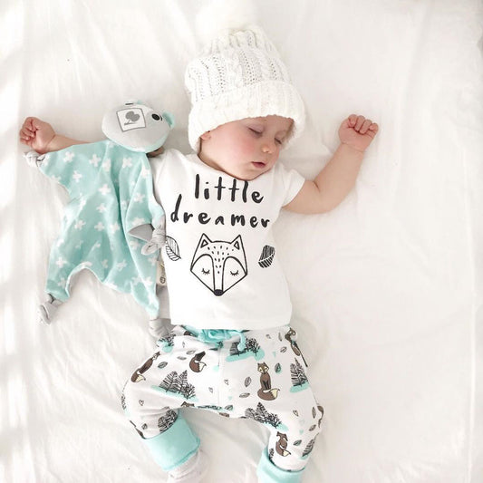 Sleeping baby wearing a newborn baby clothes set with animal print pants and white knit hat