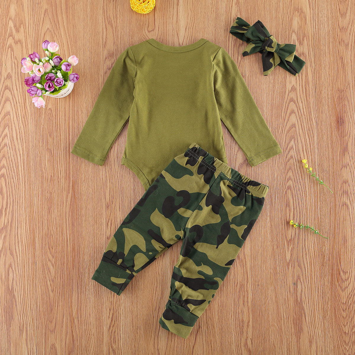 Newborn camo matching set with green long sleeve bodysuit camo pants and headband on wood background